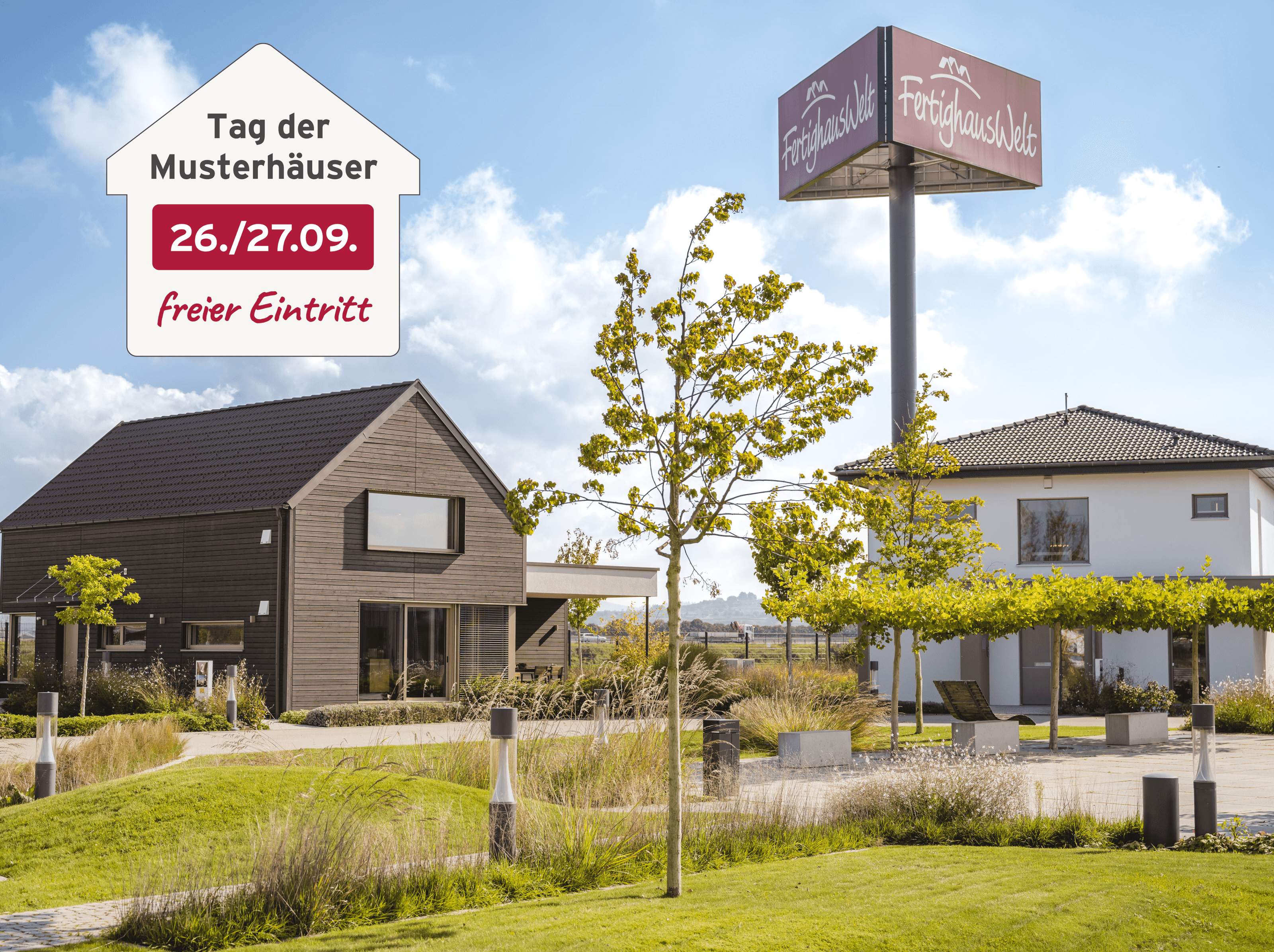 Moderne Musterhaussiedlung mit zwei Einfamilienhäusern, gepflegtem Grünbereich und großem Schild „FertighausWelt“ unter blauem Himmel; eingeblendeter Hinweis auf den „Tag der Musterhäuser“ am 26./27. September mit freiem Eintritt.