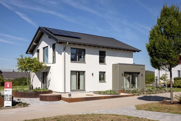 Modernes Einfamilienhaus mit Satteldach, Solaranlage, weißer Fassade, Anbau und terrassiertem Vorgarten