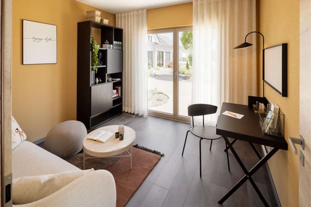 Modernes Wohnzimmer mit Home-Office-Bereich, ockerfarbenen Wänden, schwarzen Möbeln und Terrassenzugang