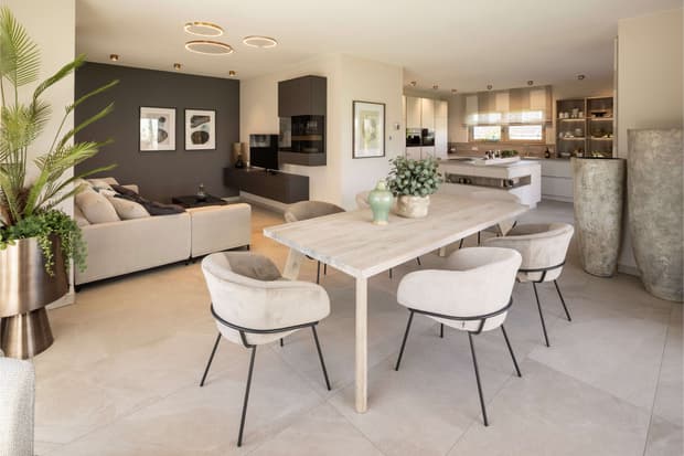 Offener Wohn-Essbereich mit moderner Küche, hellem Esstisch, Designer-Stühlen und eleganter Pflanzen-Dekoration