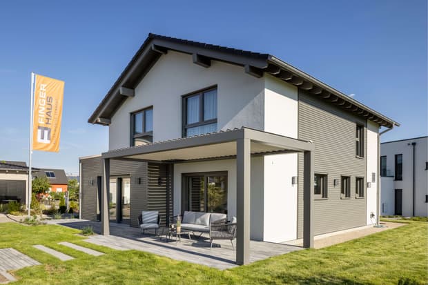 Modernes Einfamilienhaus mit Satteldach, überdachter Terrasse, Holzfassade und gepflegtem Garten im Sonnenschein
