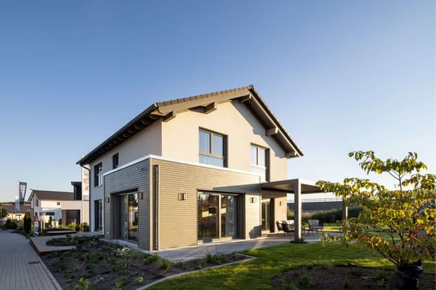 Modernes Einfamilienhaus mit Satteldach, Holzfassade, überdachter Terrasse und gepflegtem Garten bei Sonnenuntergang