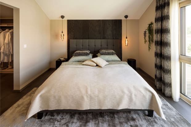 Modernes Schlafzimmer mit gepolstertem Kopfteil, Designer-Pendelleuchten, begehbarem Kleiderschrank und Pflanzen-Deko