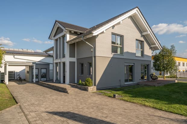 Modernes KAMPA Einfamilienhaus mit Satteldach, Carport, Erker, zweifarbiger Fassade, Pflasterweg und Garten