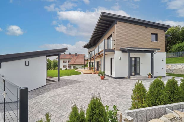 Modernes Holzhaus mit Pultdach und Mischfassade aus mineralischem Außenputz und Lärchenholz, ein Knick im Grundriss sorgt für den perfekten Ausblick