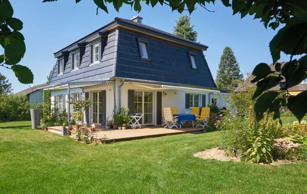 Modernes Holzhaus in barockem Stil mit Masard-Walmdach und mineralischem Außenputz