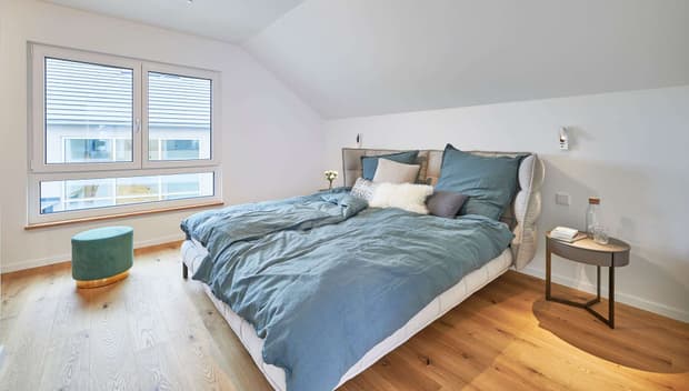 Helles Schlafzimmer mit Doppelbett, blauer Bettwäsche, Holzboden, Nachttisch, Fensterfront und modernem Design.