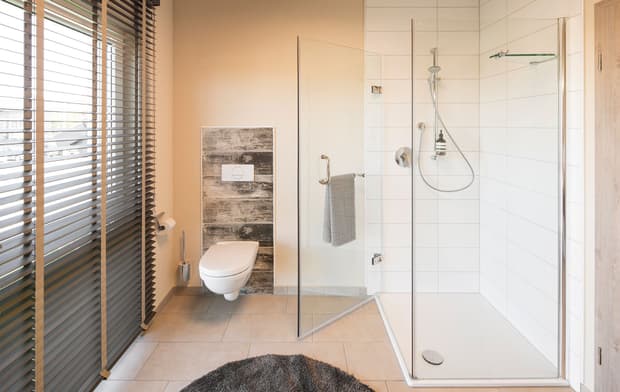 Modernes Badezimmer mit begehbarer Dusche, Glaswand, Wand-WC, Handtuchhalter, Fliesenboden und großem Fenster.