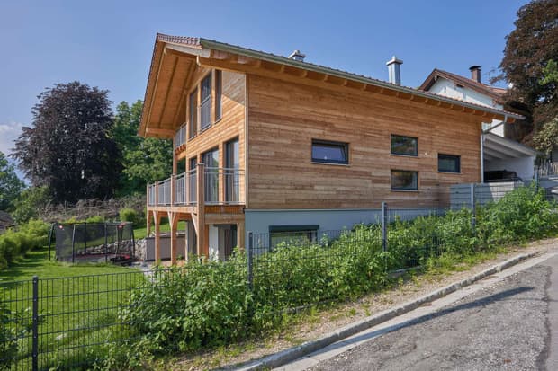 Modernes Holzhaus im Landhausstil mit Holzfassade, Holz-Alu-Fenstern und großzügigen Balkonen