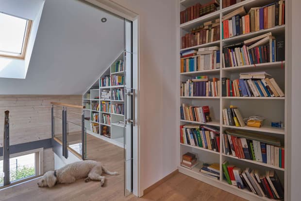 Die Bibliothek des modernen Holzhauses im Landhausstil mit Holzfassade, Holz-Alu-Fenstern und großzügigen Balkonen