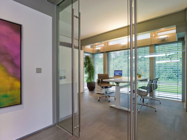 Modernes Home-Office mit Glaswänden, Designermöbeln, großen Fenstern, Jalousien und lichtdurchflutetem Arbeitsbereich