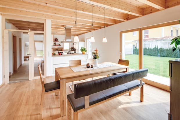 Das Esszimmer des modernen Holzhauses mit Pultdach, Putzfassade und Schiebeläden aus Lärche
