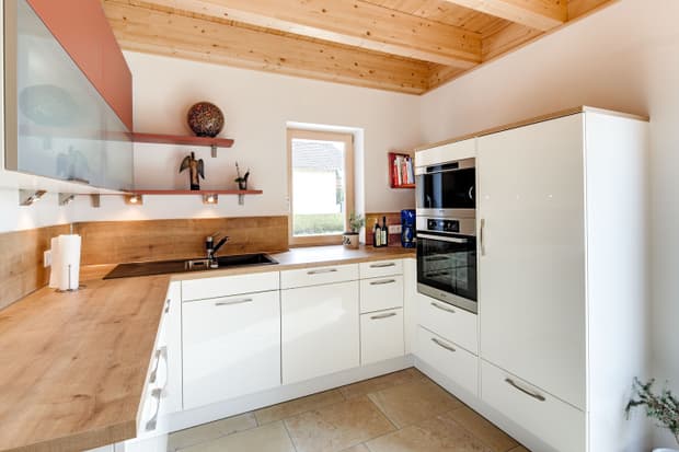 Die Küche des modernen Holzhauses mit Pultdach, Putzfassade und Schiebeläden aus Lärche
