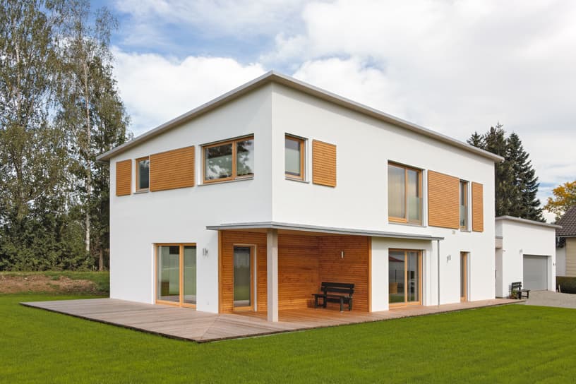 Modernes Holzhaus mit Pultdach, Putzfassade und Schiebeläden aus Lärche