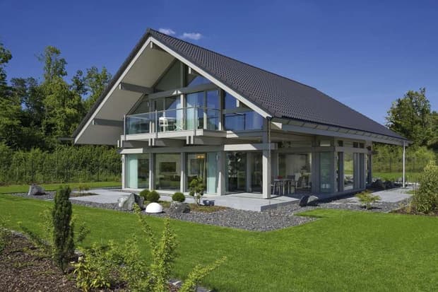 Modernes Fachwerkhaus mit Glasfassade, Satteldach, Balkon, überdachter Terrasse und großzügigem Garten