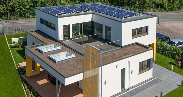 Modernes, weißes Flachdachhaus mit zwei Dachterrassen und Solarzellen in grüner Wohngegend