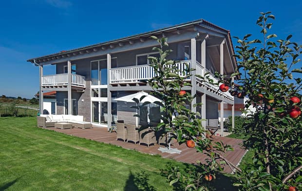 Modernes Holzhaus mit umlaufendem Balkon und Mischfassade aus Holz und Putz
