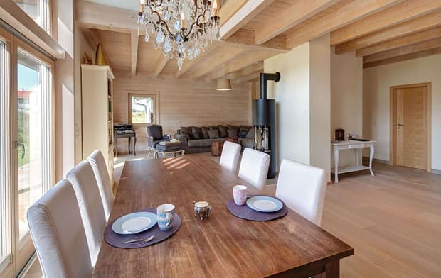 Der Wohn- und Essbereich des modernen Holzhauses mit umlaufendem Balkon und Mischfassade aus Holz und Putz