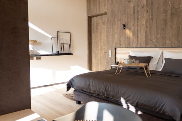 Das Schlafzimmer mit Holz-Wand des modernen und großzügigen Holzhauses, bzw. Massivholzhauses im Landhausstil im Musterhauspark in Ortenburg. Der Neubau erinnert an die Chalets im Alpenvorland, hat aber viele moderne Designelemente.