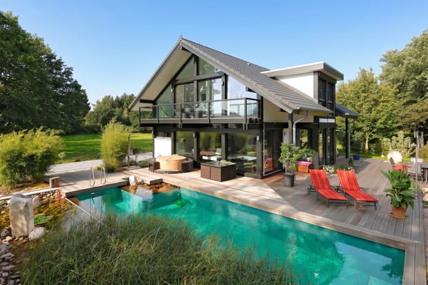 Modernes Einfamilienhaus mit großer Terrasse aus Holz, Pool mit klarem Wasser und Garten im Grünen