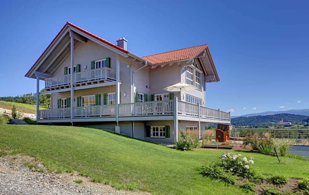 Holzhaus im Landhausstil, Holzfassade und mehrere Balkone, drei Giebel und viele Fenster