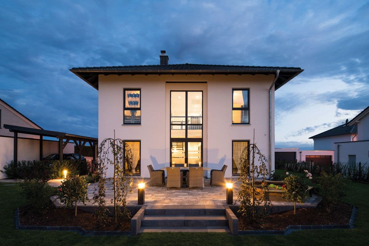 Moderne Stadtvilla mit Zeltdach, beleuchteter Terrasse und Garten