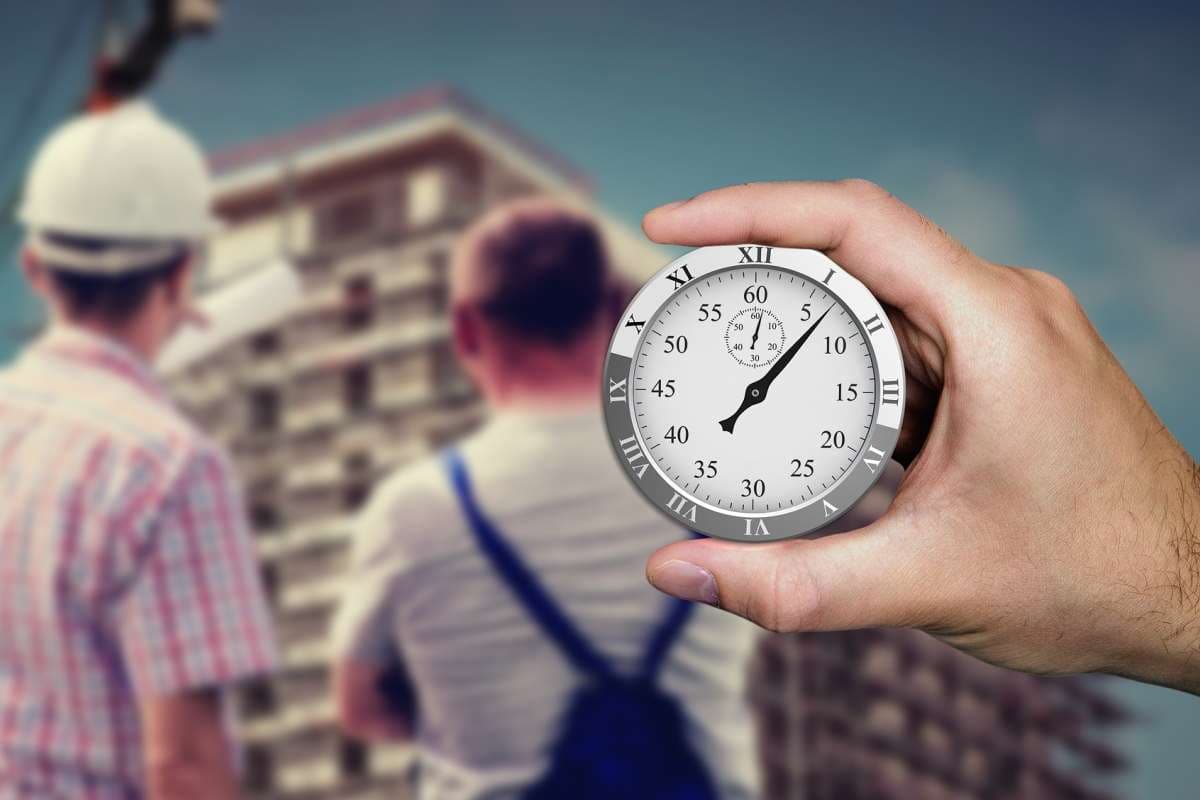 Hand mit Uhr vor verschwommener Baustelle