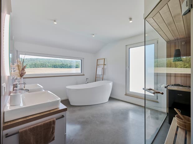 Modernes Badezimmer mit freistehender Badewanne, Doppelwaschbecken, Holzleiter und Sauna mit Glastür in Weiß und Grau