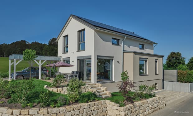 Modernes Einfamilienhaus mit weißer Fassade, Solaranlage auf dem Dach, Carport und gepflegtem Garten bei klarem Himmel