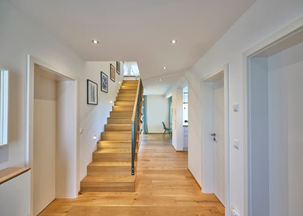 Moderner Flur mit hellen Wänden, Holzboden, Holztreppe und dekorativen Bildern in einem Wohnhaus