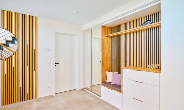 Modern gestalteter Flur mit Holzpaneelen, Einbausitzbank, weißem Schuhschrank und rundem Spiegel an der Wand