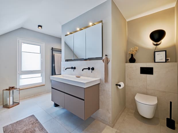 Modernes Badezimmer mit grauem Waschtisch, Wand-WC, großen Fliesen, beleuchtetem Spiegel und Fensterausschnitt