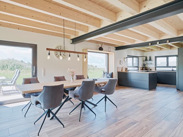 Moderner Essbereich mit Holztisch, grauen Stühlen und offener Küche mit schwarzen Fronten und Holzdecke