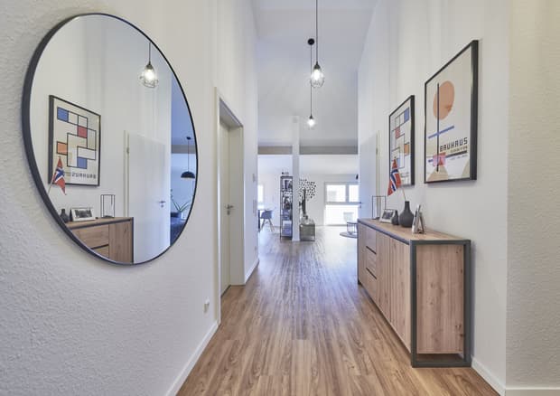 Moderner Flur mit Holzsideboard, rundem Wandspiegel, Hängelampen und abstrakter Kunst an weißen Wänden