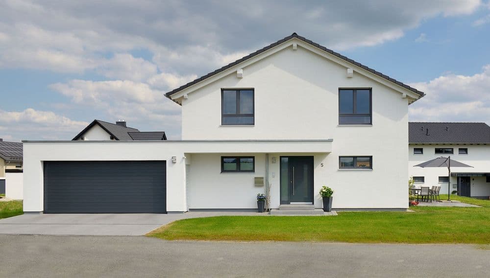 Frontalansicht eines modernen Fertighauses mit überdachtem Eingang und Garage