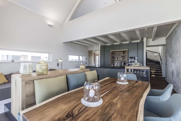 Offenes Wohn- und Esszimmer im modernen Musterhaus mit Holztisch, Designküche, heller Einrichtung und Galerie.