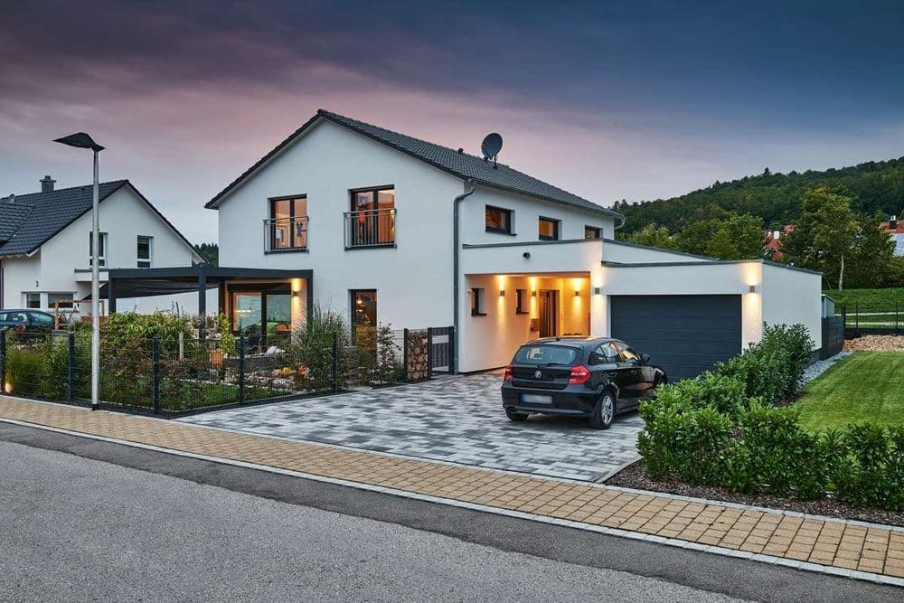 Einfamilienhaus mit Garten, Terrasse und Garage bei Dämmerung