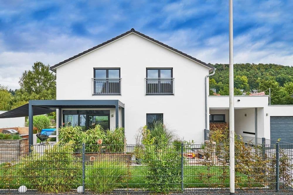 Frontalansicht eines modernen Fertighauses mit Satteldach, überdachter Terrasse und Garage