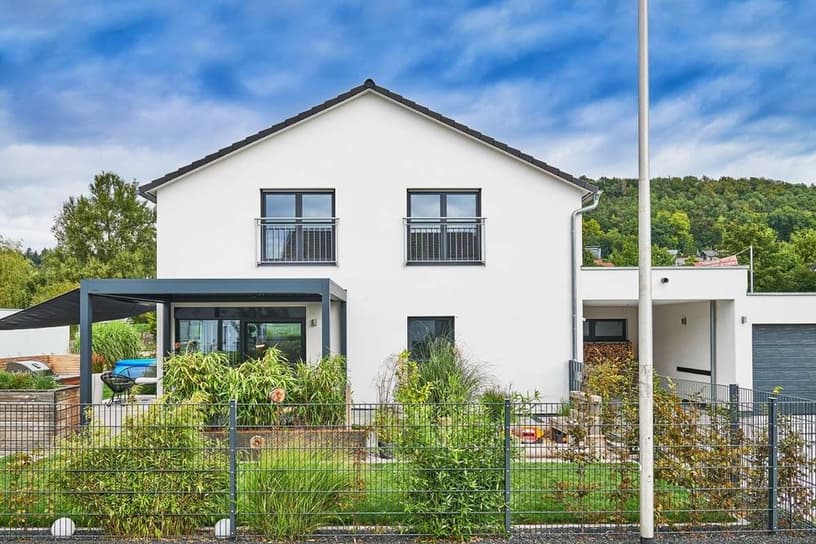 Frontalansicht eines modernen Fertighauses mit Satteldach, überdachter Terrasse und Garage