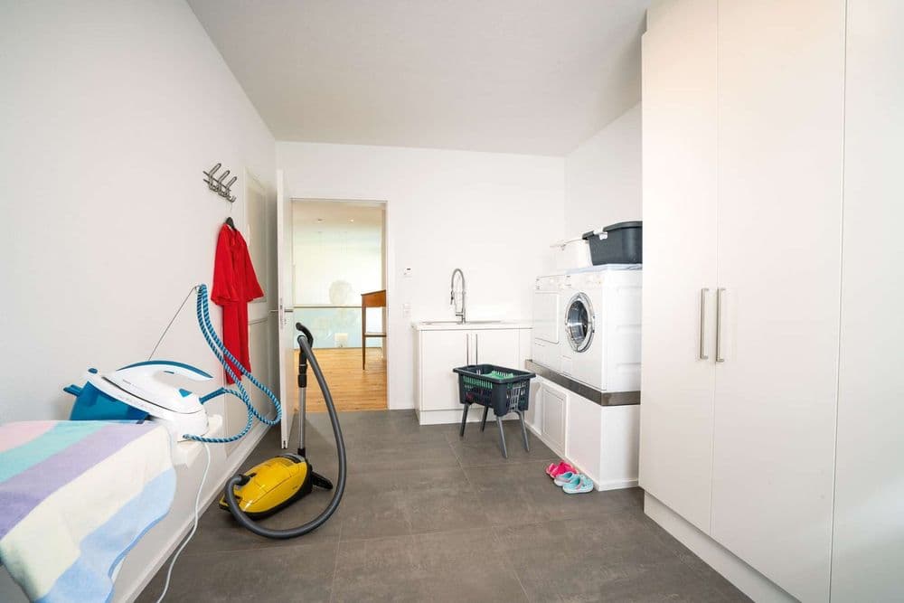 Moderner Hauswirtschaftsraum mit Waschmaschine und Staubsauger