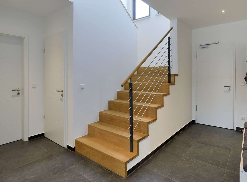 Aufgesattelte Holztreppe aus Eichenholz in Faltwerkoptik mit Stahlgeländer und Holzhandlauf.