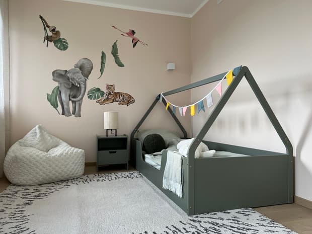 Modernes Kinderzimmer im Musterhaus mit Hausbett, Wandstickern von Tieren, Teppich und gemütlichem Sitzsack.