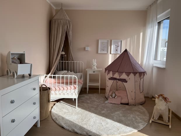 Helles Kinderzimmer im Musterhaus mit Himmelbett, Spielzelt, Teppich, Holzpferd und liebevoller Dekoration in Rosa.