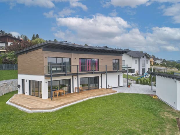 Modernes Holzhaus mit Pultdach und Mischfassade aus mineralischem Außenputz und Lärchenholz, ein Knick im Grundriss sorgt für den perfekten Ausblick
