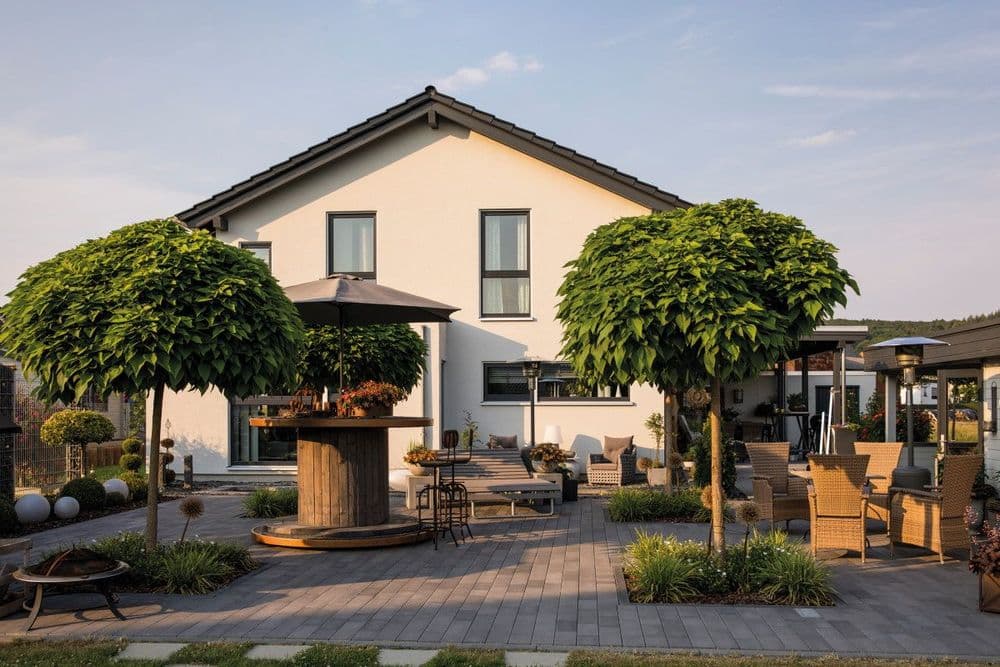 Modernes Fertighaus mit Garten und großem, gepflasterten Außenbereich