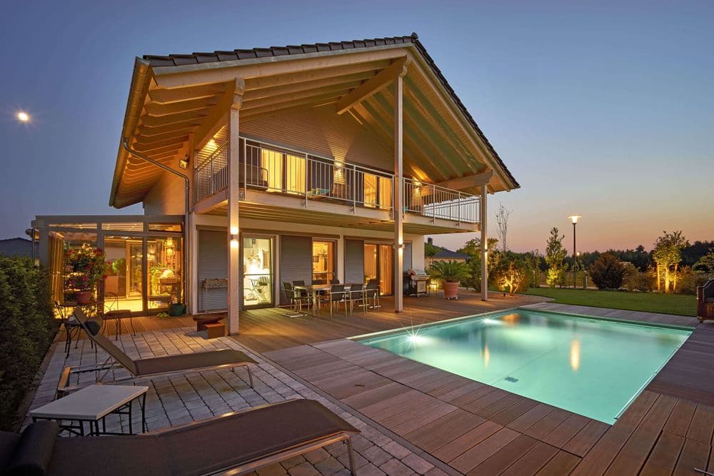 Quadratischer Pool mit Außenbeleuchtung vor einem Holzhaus