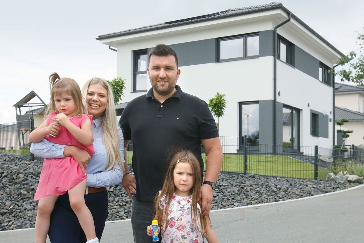 Glückliche Baufamilie vor dem neuen Eigenheim