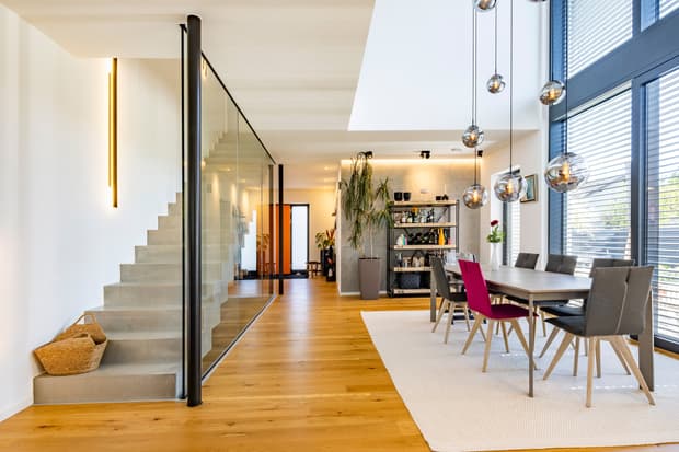 Moderner Essbereich mit Holzboden, Glaswand, grauem und rotem Stuhl, Metallregal und großen Fensterfronten mit Jalousien