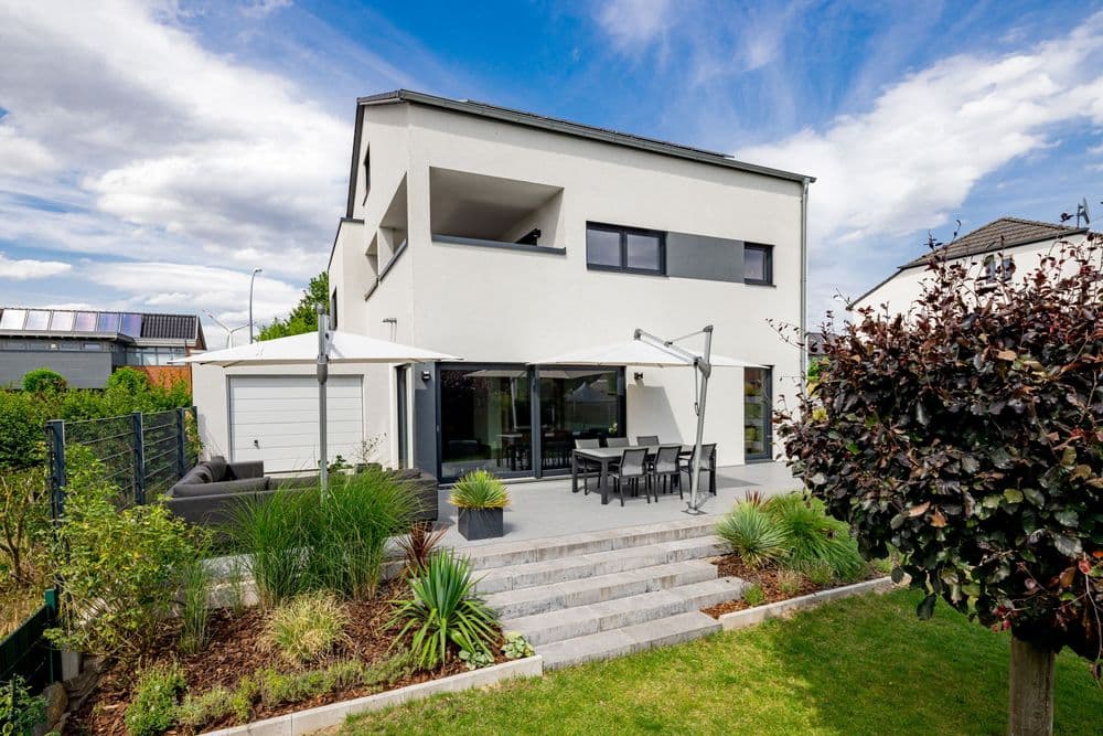 Modernes LUXHAUS Fertighaus mit Satteldach, überdachter Terrasse und Garten