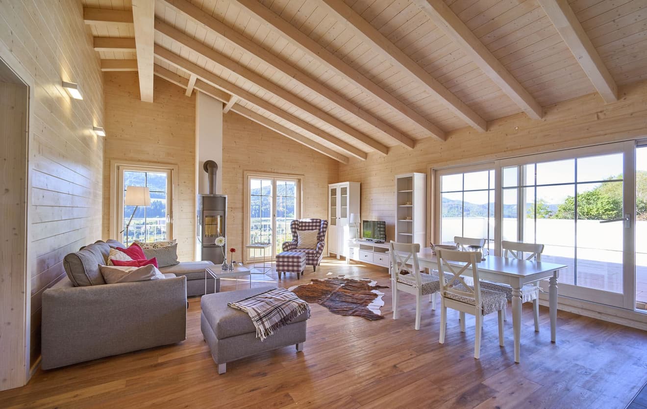 Das Wohnzimmer besitzt einen Kamin sowie Panoramasicht auf den Garten. 
